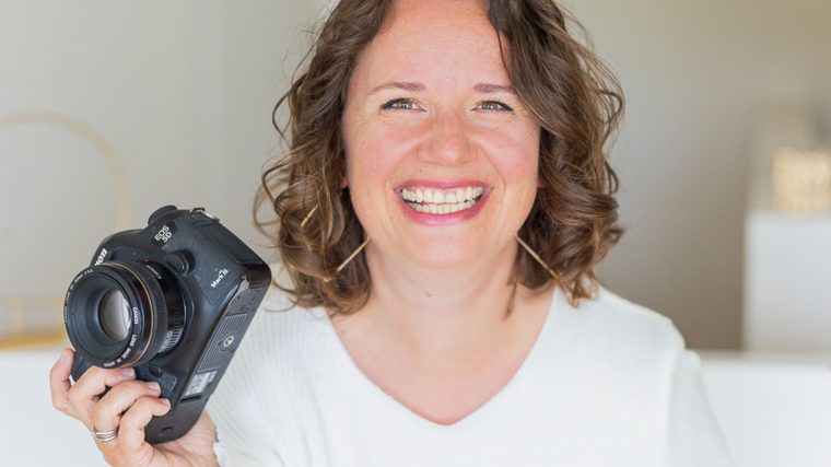 Fotografin Karin Ahamer im Weinviertel, lächelnd und mit Kamera in der Hand, bereit für ein professionelles Porträtshooting.
