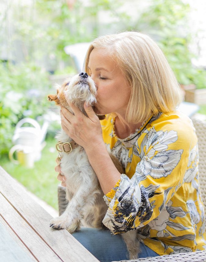 Foto einer blonden Frau die liebevollen ihren kleinen Hund küsst