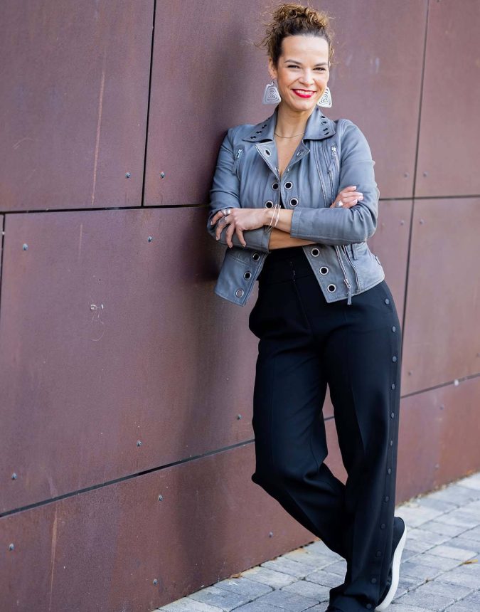 Foto einer Frau in modernem Lifestyle Look die an einer Wand lehnt