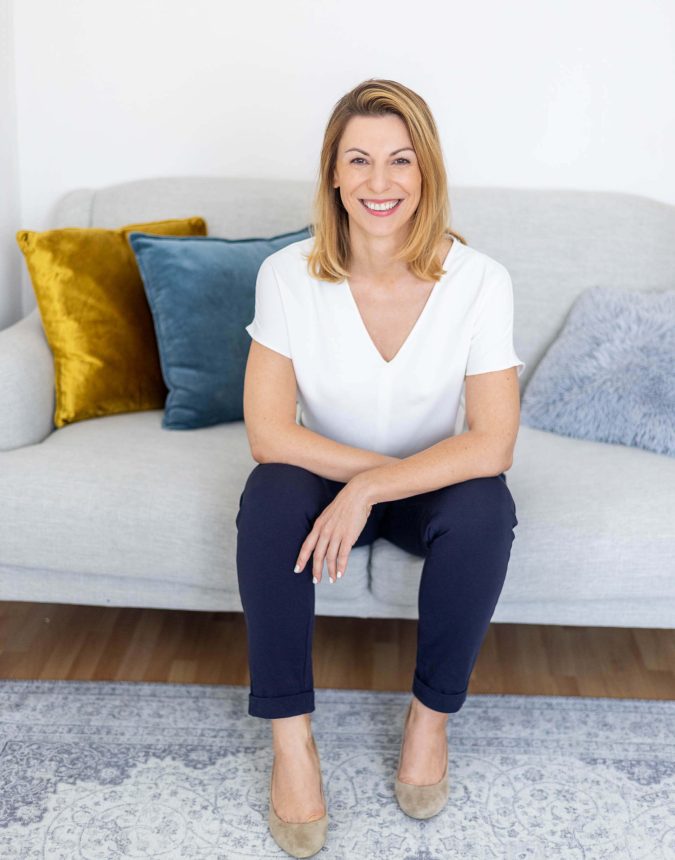 Foto einer Frau die leger und lächend auf der Couch sitzt