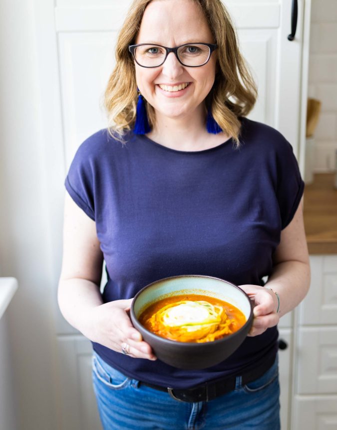 Portrait einer Frau in der Küche die eine Suppenschüssel in die Kamera zeigt