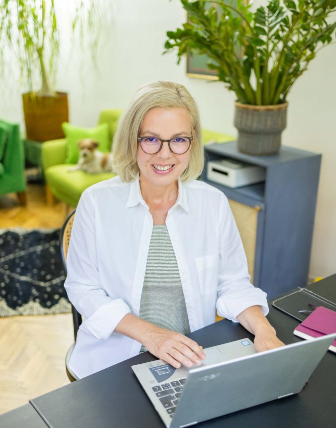 Portrait einer Frau die mit Laptop am Schreibtisch sitzt