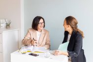 Professionelles Frauenportrait mit 2 Unternehmerinnen die am Schreibtisch plaudern